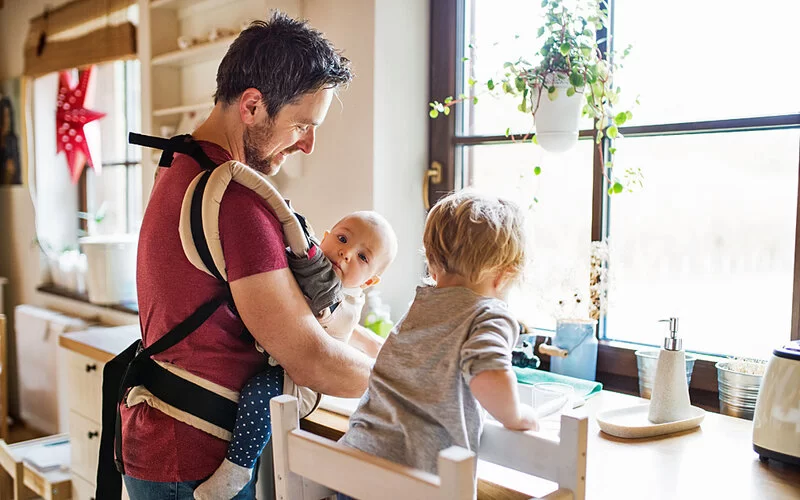 Vater mit seinen zwei Kindern beim Spülen des Geschirrs in der Küche.