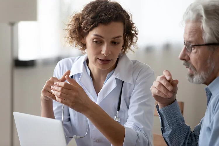 Allgemeinmedizinerin bespricht Laborergebnisse mit einem Patienten.