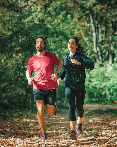 Ein Mann und eine Frau joggen durch einen Wald.