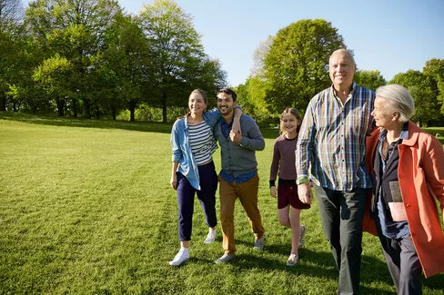 Eine fünfköpfige Familie spaziert gemeinsam über eine Wiese. Als AOK-Versicherte haben sie ein Mitbestimmungsrecht.