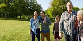 Eine fünfköpfige Familie spaziert gemeinsam über eine Wiese. Als AOK-Versicherte haben sie ein Mitbestimmungsrecht.