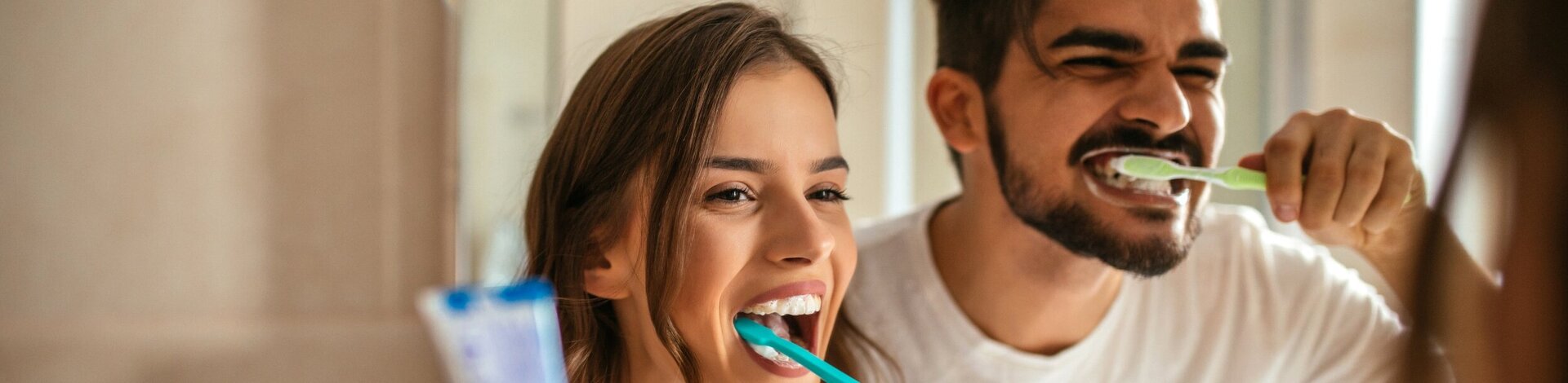 Mann und Frau putzen ihre schönen Zähne und haben Spaß dabei.