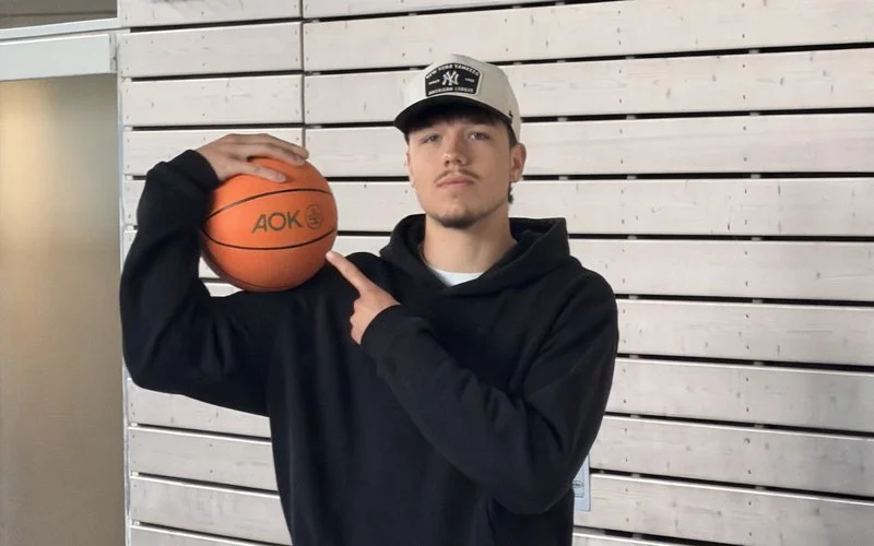 Jugendlicher hält einen AOK-Basketball in einer Sporthalle und unterstützt das Schulprojekt Ahorn@school zur Bewegungsförderung.