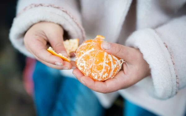 Eine Frau pellt eine gesunde Mandarine.