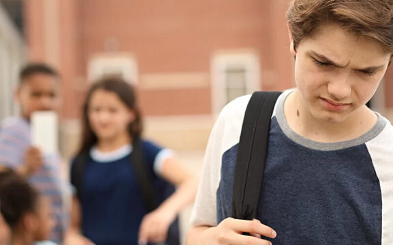 Junge mit Tourette-Syndrom geht traurig vom Schulhof weg, weil er gemobbt wurde.