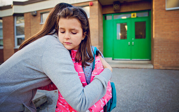 Mädchen hat Angst zur Schule zu gehen und umarmt ihre Mutter traurig.
