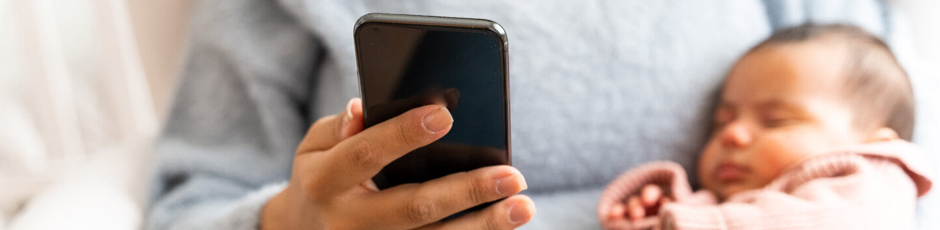 Eine Frau mit einem Baby am Arm telefoniert. Die AOK berät Eltern telefonisch mit wichtigen Informationen zur Gesundheit ihrer Kinder.