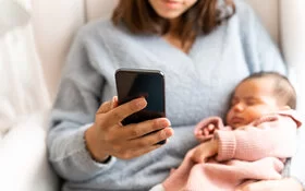 Eine Frau mit einem Baby am Arm telefoniert. Die AOK berät Eltern telefonisch mit wichtigen Informationen zur Gesundheit ihrer Kinder.