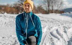 Ein Mann dehnt sich vor dem Joggen im Winter.