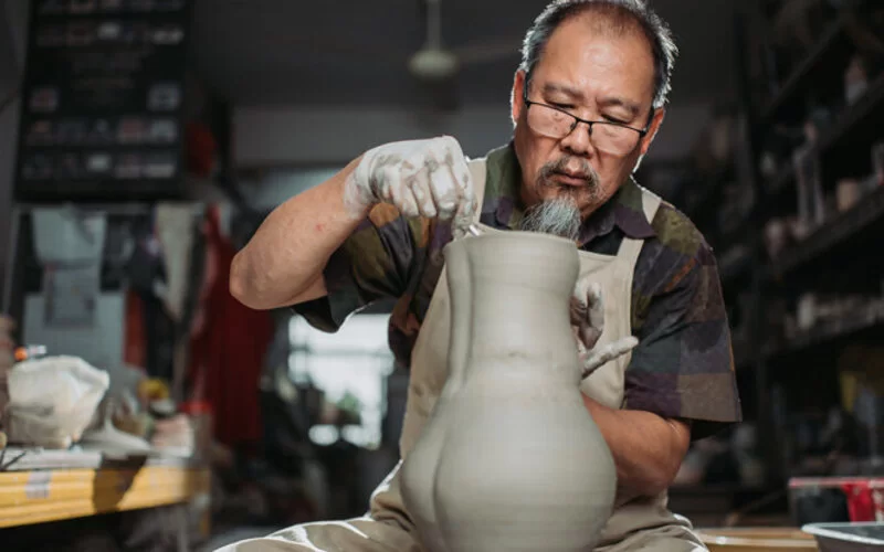 Ein älterer Mann, der endlich Rentner ist, töpfert eine große Vase.