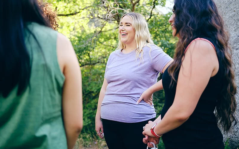 Frauen in sportlicher Kleidung stehen beisamen und lachen.