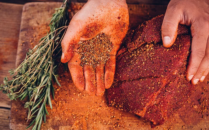 Ein großes Stück Grillfleisch wird mit einer selbstgemachten Trockenmarinade eingerieben.