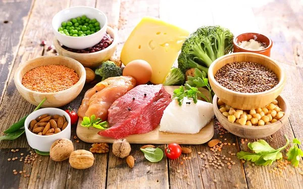 Ein reichlich gedeckter Tisch mit aminosäurehaltigen Lebensmitteln wie Fleisch, Nüssen und Eiern.