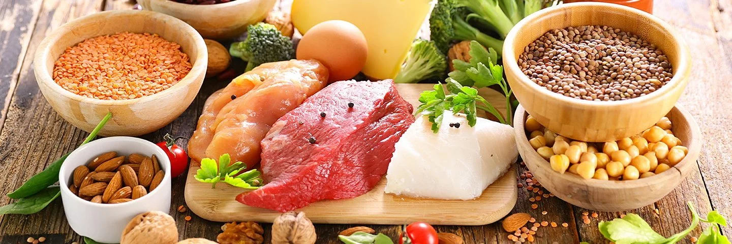 Ein reichlich gedeckter Tisch mit aminosäurehaltigen Lebensmitteln wie Fleisch, Nüssen und Eiern.