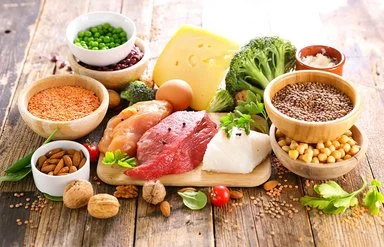 Ein reichlich gedeckter Tisch mit aminosäurehaltigen Lebensmitteln wie Fleisch, Nüssen und Eiern.