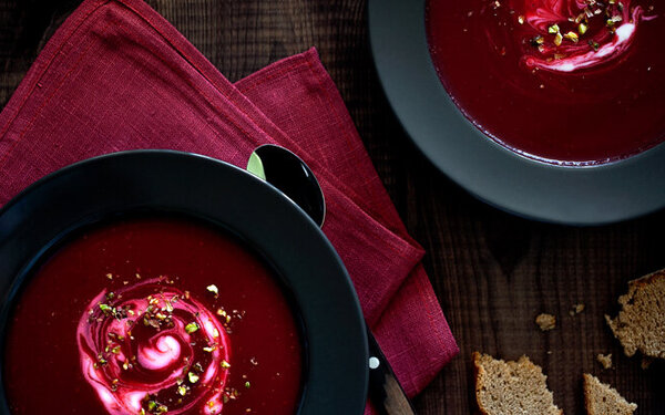 Rote-Bete-Suppe mit saurer Sahne als Vorspeise an Weihnachten in schwarzen Suppentellern serviert. 