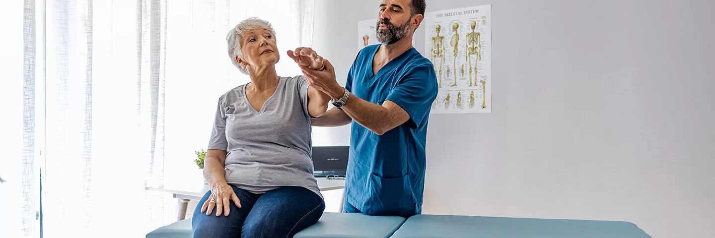 Physiotherapeut macht Übung mit einer Demenzerkrankten.