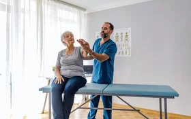 Physiotherapeut macht Übung mit einer Demenzerkrankten.