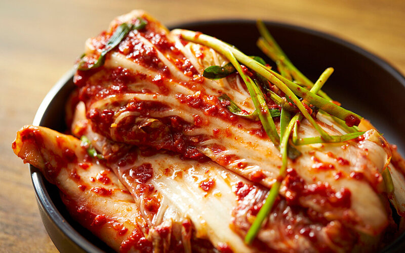 Kimchi mit roter Paste angerichtet in einem tiefen Teller.