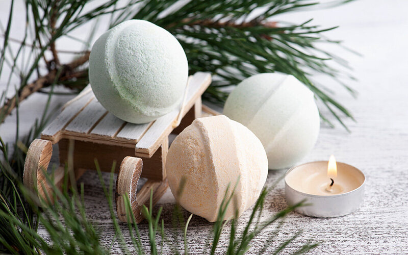 Drei selbstgemachte Badekugeln mit winterlich weihnachtlicher Dekoration.
