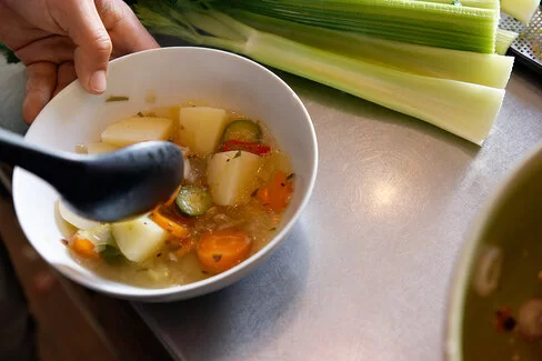 Eine Hand hält eine Schale mit einer Brühe mit Gemüse. Bei der richtigen Ernährung unterstützt Sie die AOK.
