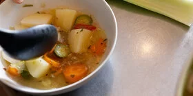 Eine Hand hält eine Schale mit einer Brühe mit Gemüse. Bei der richtigen Ernährung unterstützt Sie die AOK.