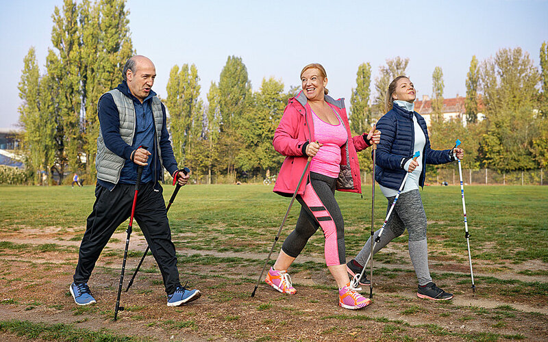 Drei Menschen mittleren Alters machen Nordic Walking – eine Sportart die zu ihnen passt.