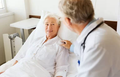 Ein Arzt spricht mit einer älteren Patientin in einem Krankenhausbett.