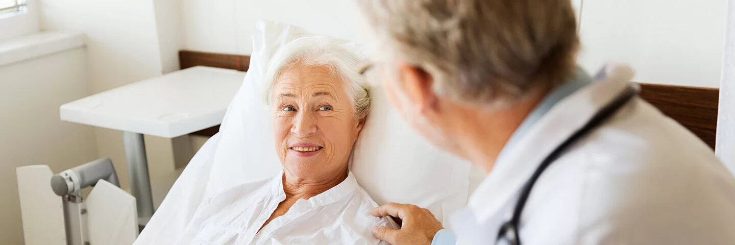 Ein Arzt spricht mit einer älteren Patientin in einem Krankenhausbett.