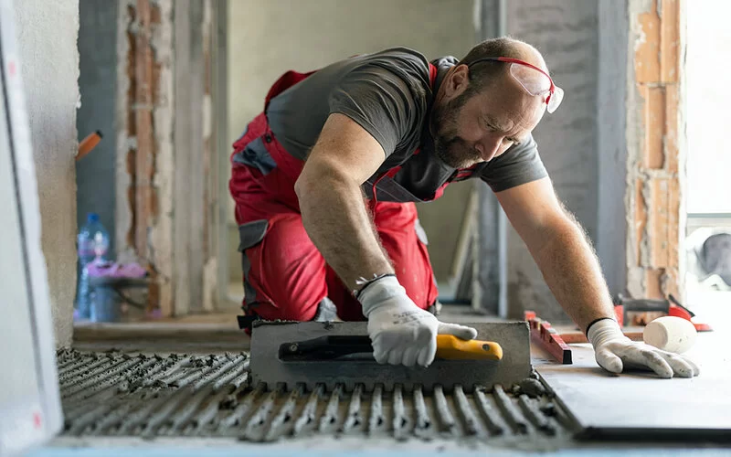 Fliesenleger arbeiten oft kniend. Durch die ständige Belastung, sind sie anfälliger als andere Berufsgruppen für Schleimbeutelentzündungen am Knie.