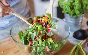 Mann bereitet knackig-frischen Salat in einer Schüssel zu.