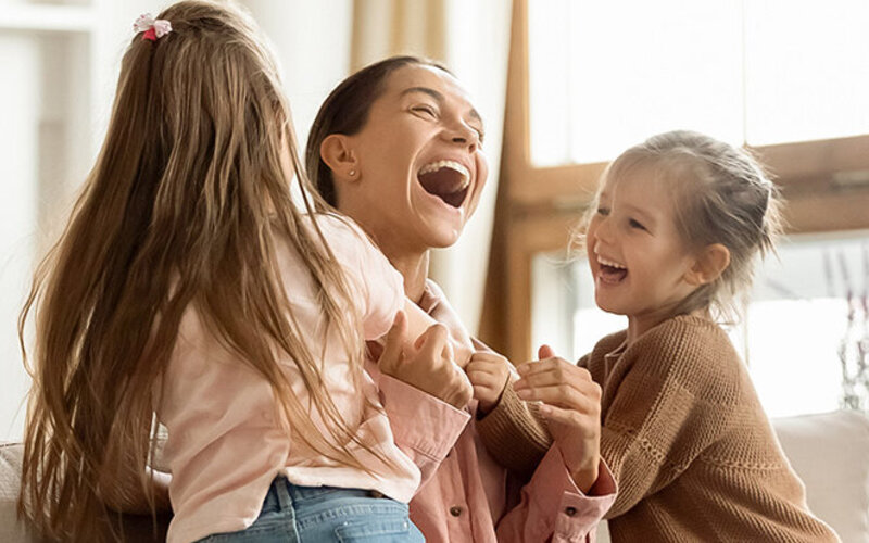 Mutter weiß, Lachen ist gesund und tobt fröhlich mit ihren zwei kleinen Kindern.