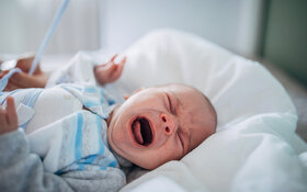 Ein Baby mit Schlafregression liegt auf dem Rücken und weint.