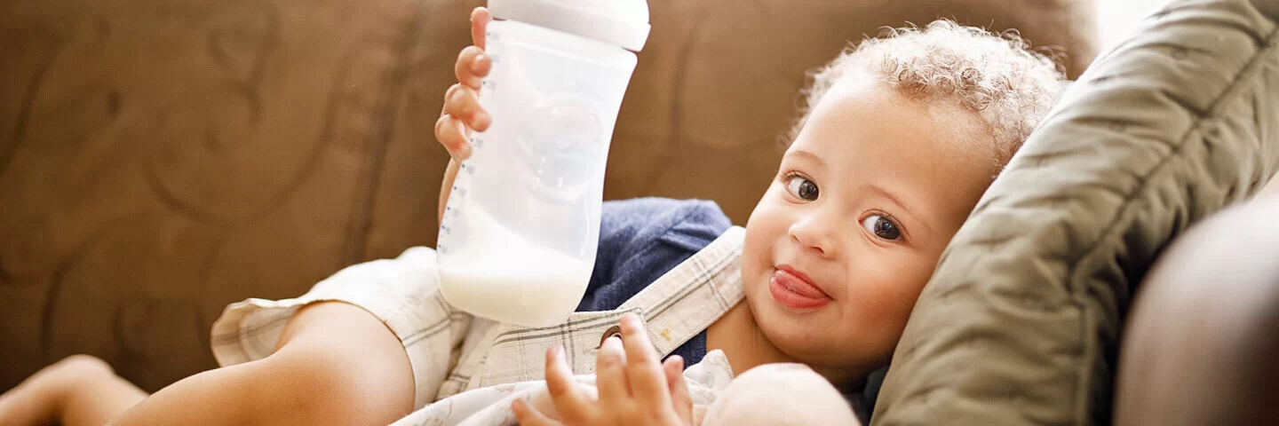 Baby trinkt Muttermilch aus Fläschchen, weil die Mutter mit dem Abstillen begonnen hat.