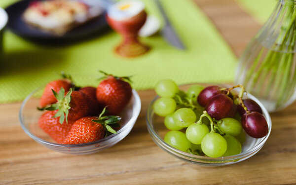 Erdbeeren und Trauben in einer Schale auf einem Frühstückstisch
