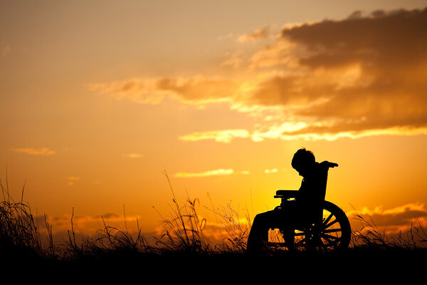 Kleiner Junge sitzt traurig im Rollstuhl.