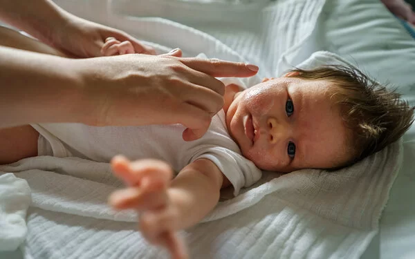 Eine Frau cremt das Gesicht eines Babys mit Neurodermitis ein.