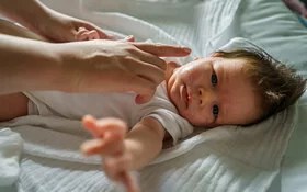 Eine Frau cremt das Gesicht eines Babys mit Neurodermitis ein.