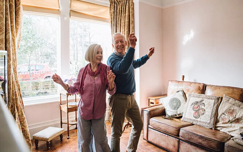 Zwei Senioren tanzen miteinander zu Hause.