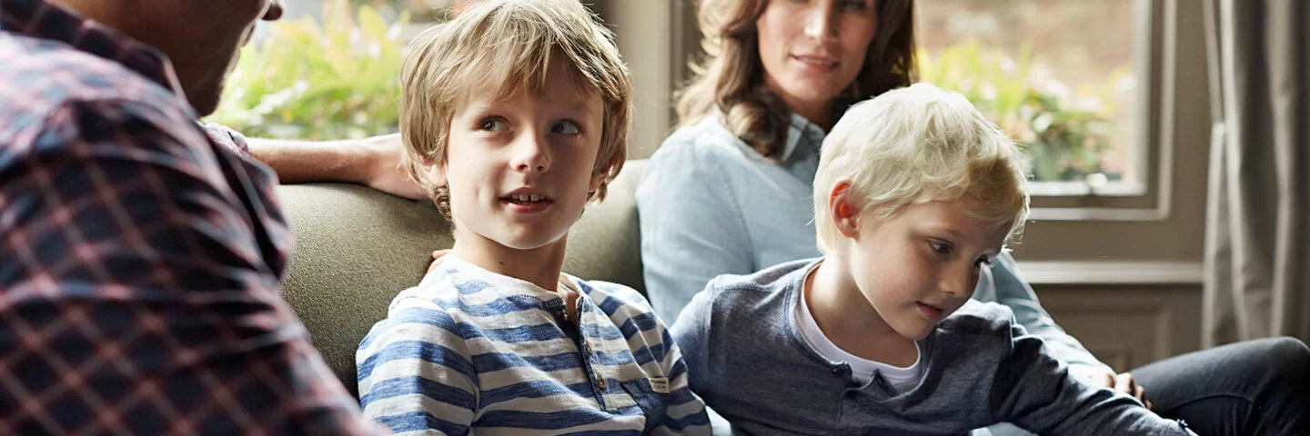 Eine vierköpfige Familie sitzt entspannt auf dem Sofa.