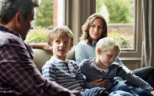 Eine vierköpfige Familie sitzt entspannt auf dem Sofa.