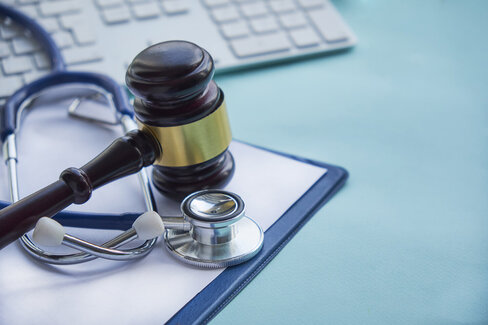 Neben einem Stethoskop liegt der Hammer eines Richters. Lesen Sie, wie man Fehlverhalten im Gesundheitswesen bekämpfen kann.