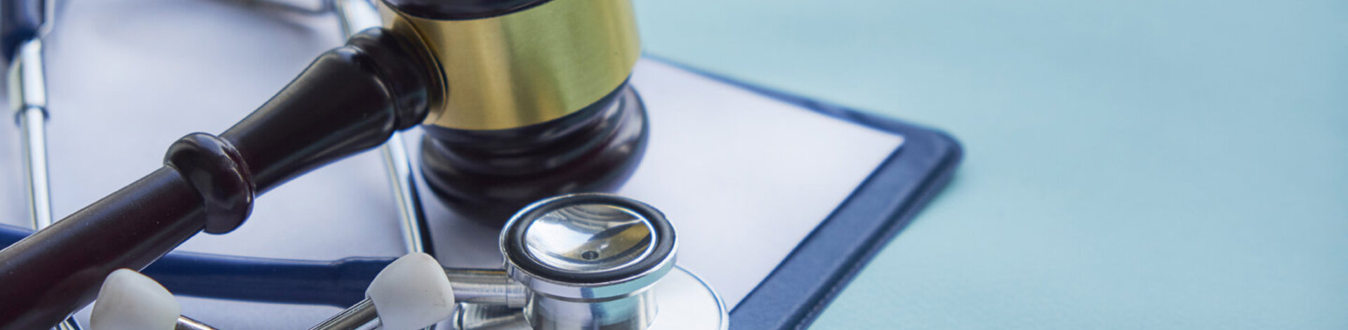 Neben einem Stethoskop liegt der Hammer eines Richters. Lesen Sie, wie man Fehlverhalten im Gesundheitswesen bekämpfen kann.
