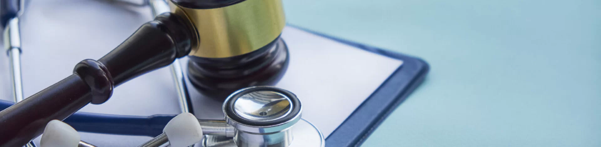 Neben einem Stethoskop liegt der Hammer eines Richters. Lesen Sie, wie man Fehlverhalten im Gesundheitswesen bekämpfen kann.