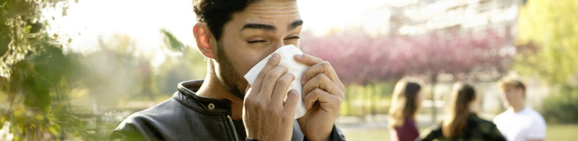 Ein junger Mann ist im Freien und putzt seine Nase. Was gegen eine Pollenallergie hilft, verrät der Beitrag. 