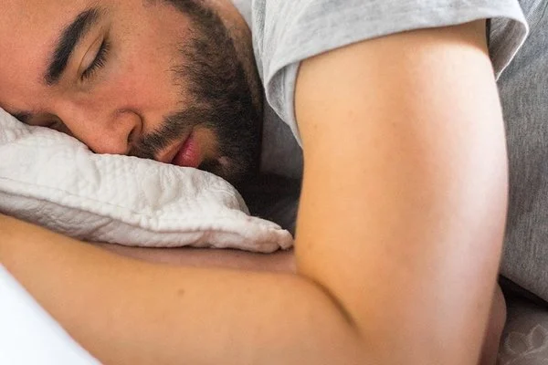 Ein junger Mann schläft in seinem Bett.