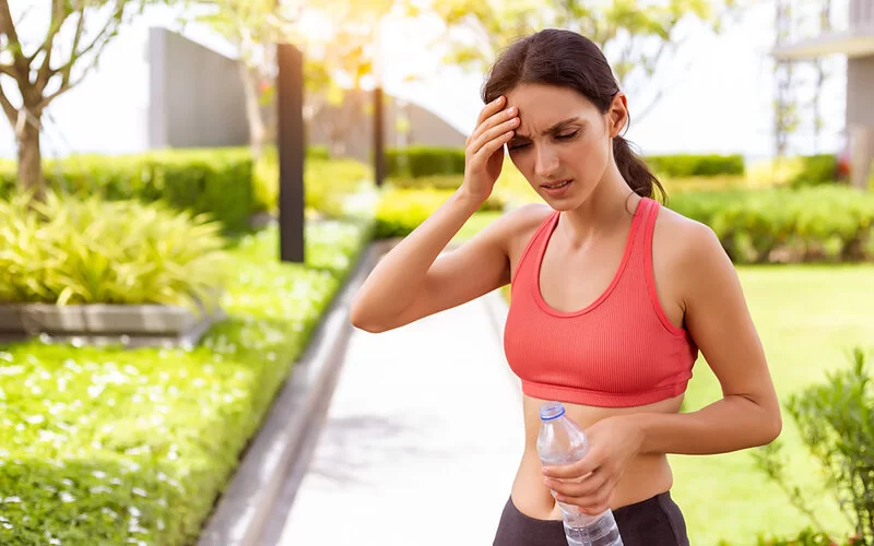 Junge Sportlerin leidet unter Kreislaufproblemen an einem heißen Sommertag.