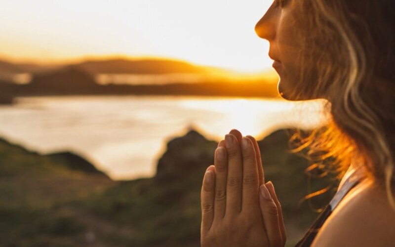 Frau meditiert in der Natur und macht sich positive Gedanken.