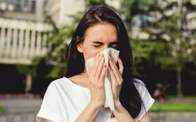 Eine Frau niest, sie hatte eine Sommergrippe.