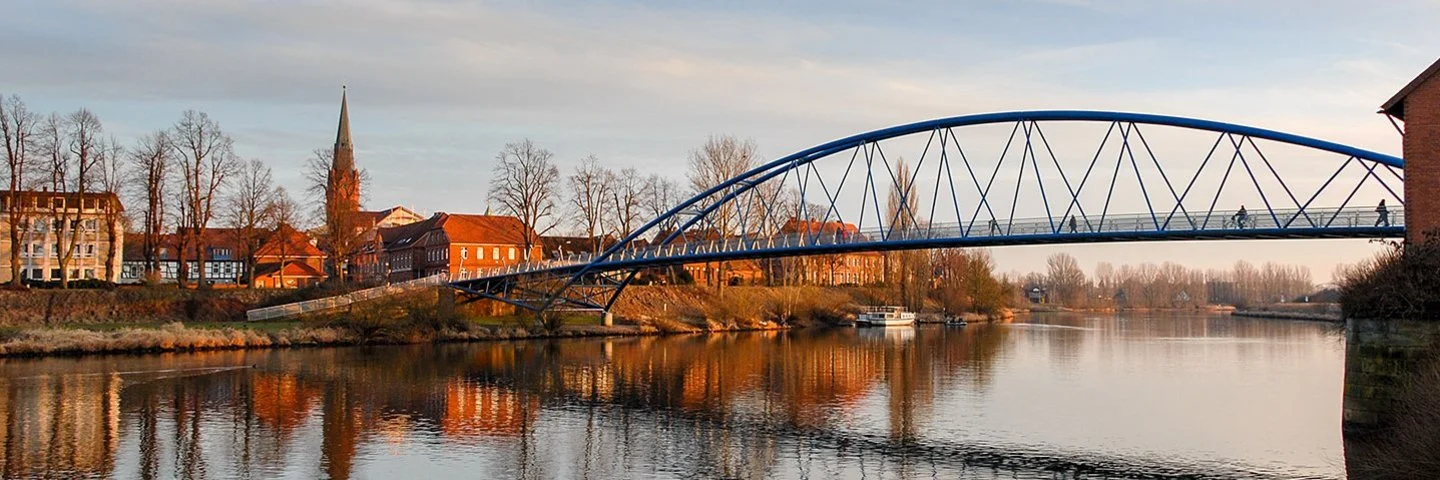 Abendsonne in der Kleinstadt Nienburg mit Kirche und Fußgängerbrücke an der Weser
